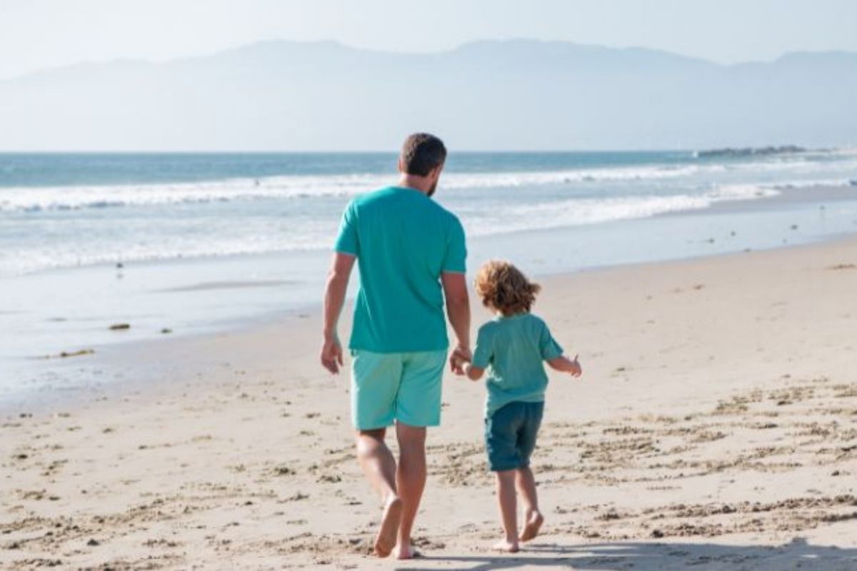 Father and child walking along the beach.