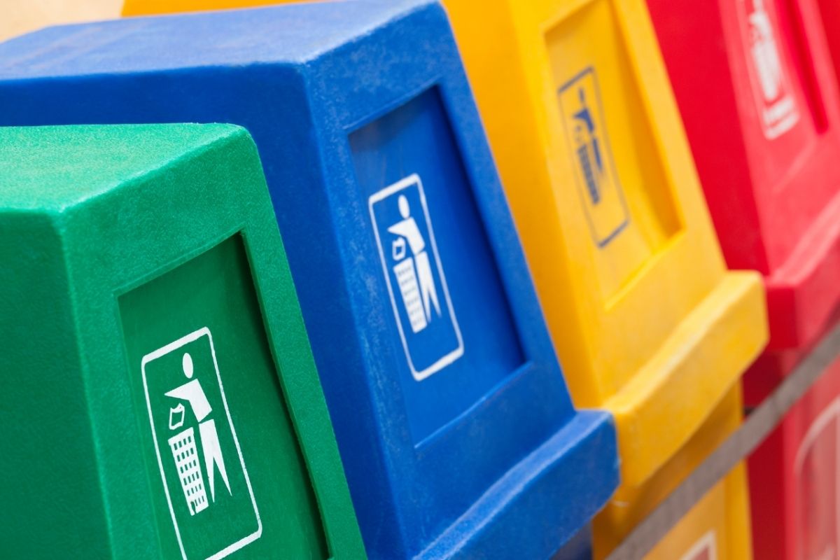 Green, Blue, Yellow and Red recycling bins lined up in a row.